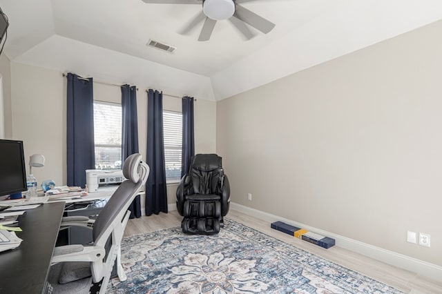 home office with lofted ceiling, a ceiling fan, visible vents, baseboards, and light wood-type flooring