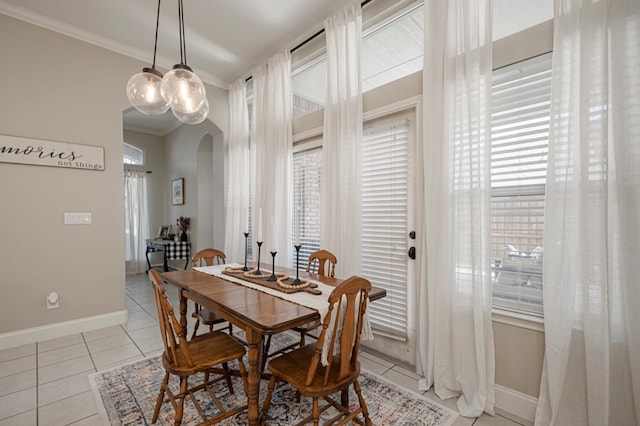 dining space with baseboards, arched walkways, ornamental molding, and light tile patterned flooring