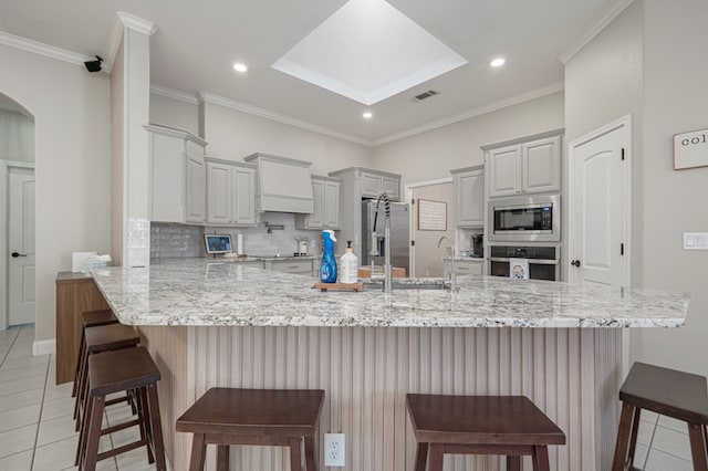 kitchen featuring a peninsula, a sink, visible vents, appliances with stainless steel finishes, and backsplash