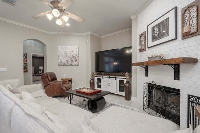 tiled living room with arched walkways, a fireplace, a ceiling fan, and crown molding