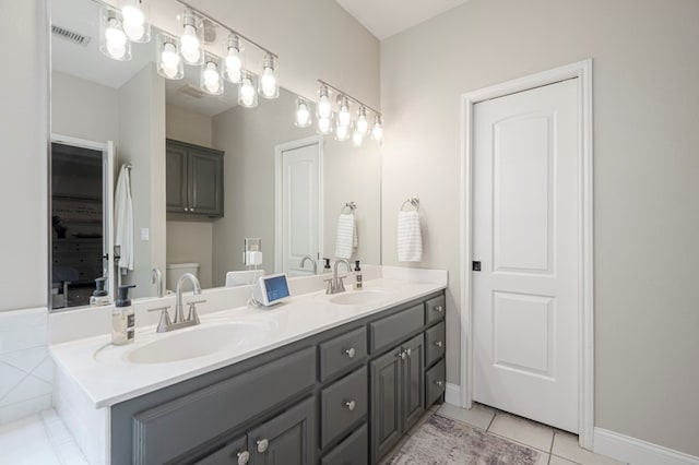 bathroom with double vanity, visible vents, a sink, and tile patterned floors