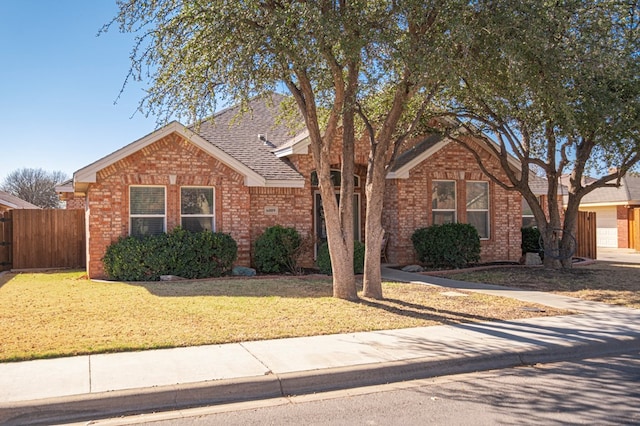 single story home featuring roof with shingles, brick siding, a front lawn, and fence