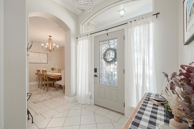 entryway with an inviting chandelier, baseboards, light tile patterned floors, and arched walkways