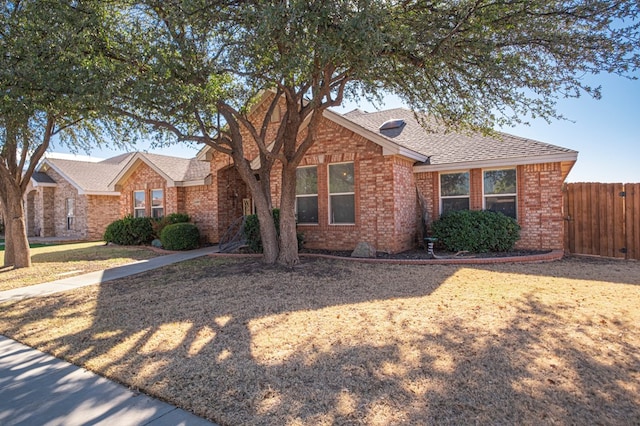 ranch-style house featuring brick siding, a shingled roof, and fence