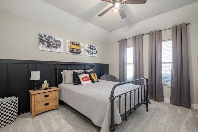 bedroom with a ceiling fan, wainscoting, light colored carpet, and vaulted ceiling