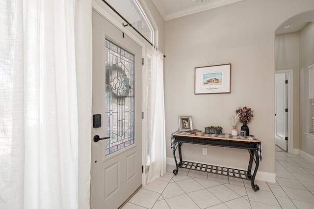 foyer entrance with baseboards, arched walkways, tile patterned flooring, and crown molding