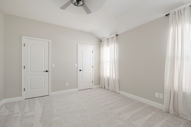 unfurnished bedroom featuring light carpet, lofted ceiling, a ceiling fan, and baseboards