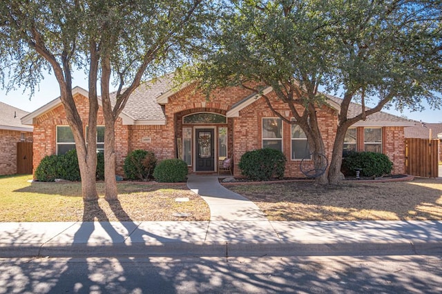 ranch-style home with roof with shingles, a gate, fence, a front lawn, and brick siding