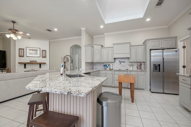 kitchen with visible vents, light tile patterned flooring, a sink, a peninsula, and stainless steel fridge with ice dispenser