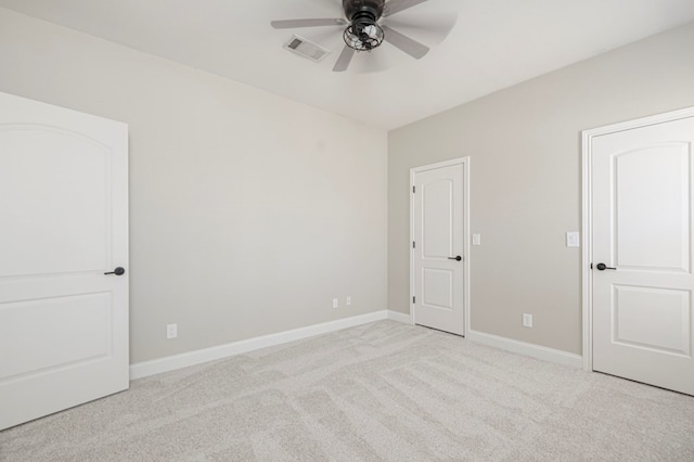 empty room with baseboards, visible vents, a ceiling fan, and light colored carpet