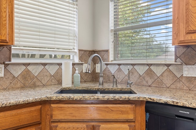3402 Alicia Ct, Midland, TX 79707 - kitchen with dishwashing machine, brown cabinets, tasteful backsplash, and light stone counters
