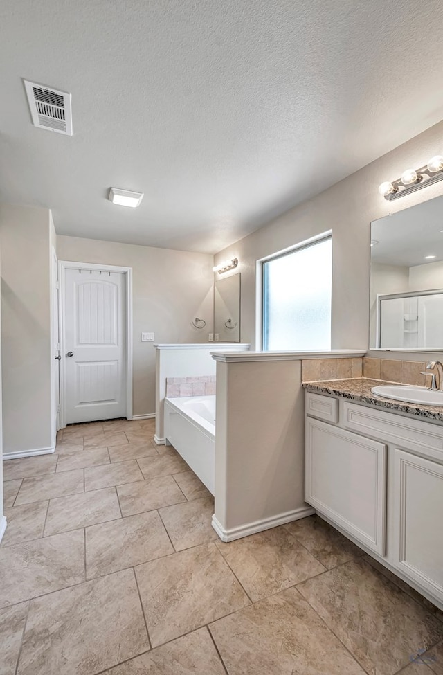 bathroom with vanity, a textured ceiling, and a bathtub