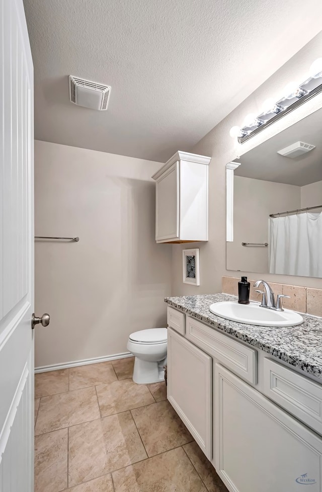 bathroom featuring a textured ceiling, vanity, and toilet