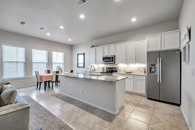 kitchen with white cabinets, sink, decorative backsplash, an island with sink, and stainless steel appliances