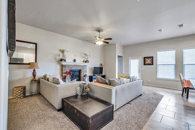 living room with a fireplace, light tile patterned floors, and ceiling fan