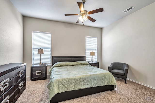 bedroom featuring ceiling fan, light carpet, and multiple windows