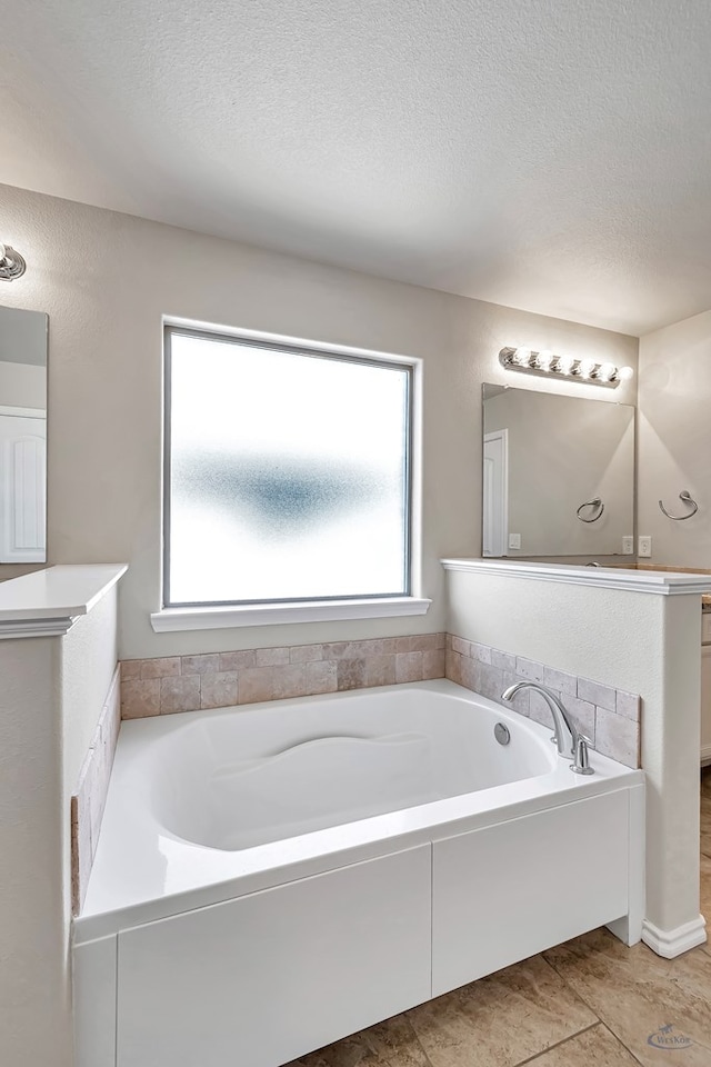 bathroom featuring tile patterned floors, vanity, a bath, and a textured ceiling