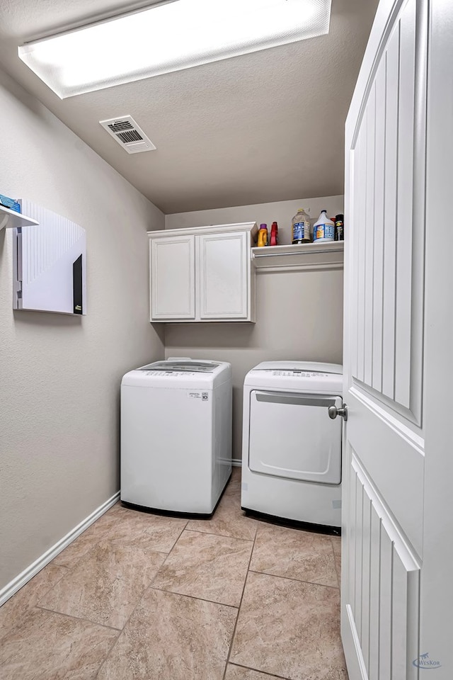 laundry room with cabinets, a textured ceiling, and washing machine and dryer