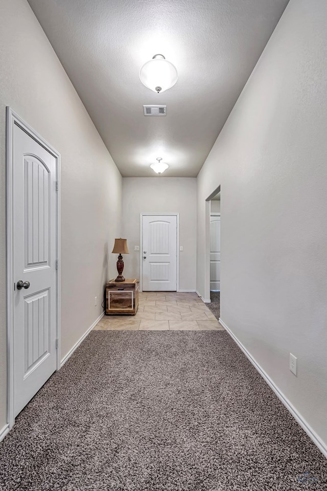 corridor featuring a textured ceiling and light carpet