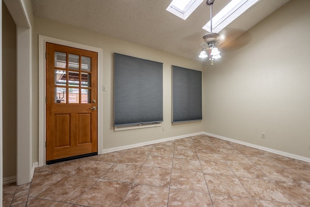 foyer entrance featuring a skylight, tile patterned floors, baseboards, a ceiling fan, and a textured ceiling