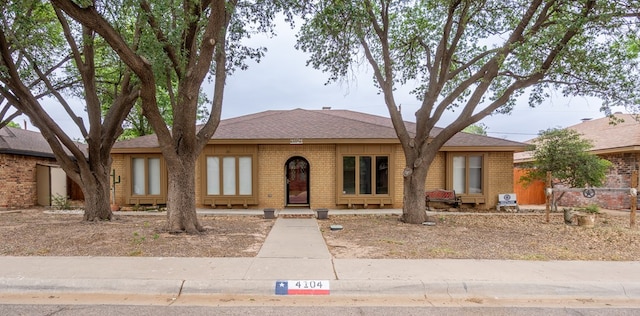 view of front of home featuring roof with shingles and brick siding
