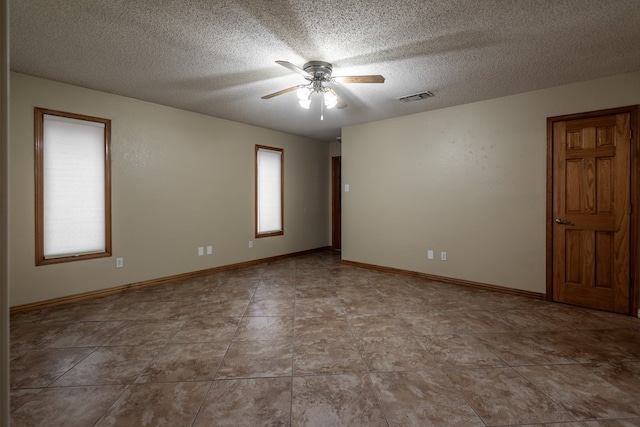 unfurnished room featuring a textured ceiling, visible vents, ceiling fan, and baseboards