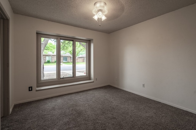 spare room with baseboards, dark carpet, ceiling fan, and a textured ceiling