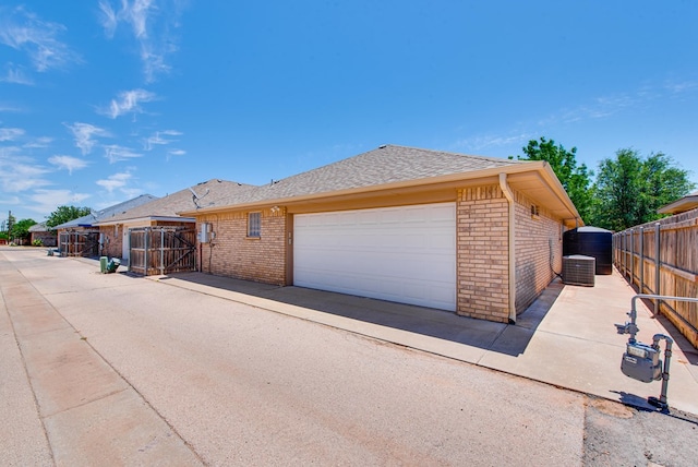 view of home's exterior featuring brick siding, fence, a gate, and an attached garage