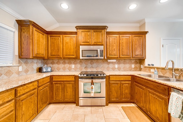 kitchen with appliances with stainless steel finishes, a sink, brown cabinetry, crown molding, and recessed lighting