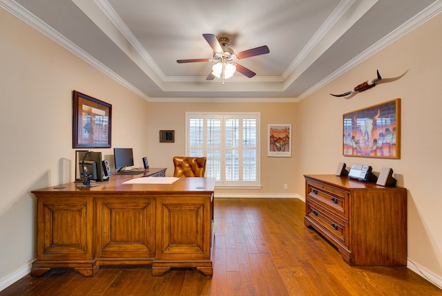 office space with a raised ceiling, dark wood-style flooring, ceiling fan, baseboards, and crown molding