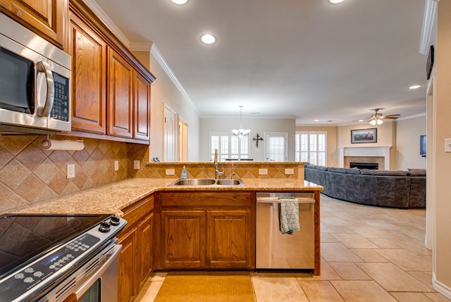 kitchen with appliances with stainless steel finishes, a sink, a peninsula, a fireplace, and ornamental molding