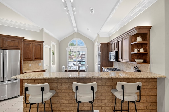 5703 Devlin Pl, Midland, TX 79707 - kitchen with stainless steel appliances, a chandelier, open shelves, decorative backsplash, and a kitchen breakfast bar