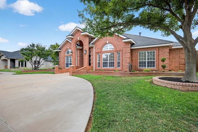 5703 Devlin Pl, Midland, TX 79707 - traditional-style house with brick siding, a front yard, a shingled roof, and driveway
