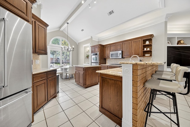 5703 Devlin Pl, Midland, TX 79707 - kitchen with stainless steel appliances, tasteful backsplash, a peninsula, a kitchen bar, and crown molding
