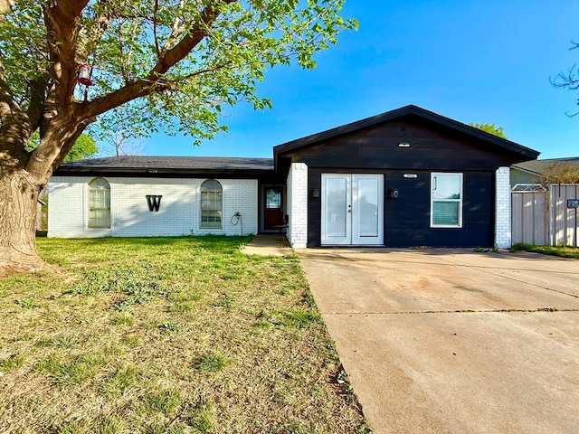 single story home with concrete driveway, a front yard, and brick siding