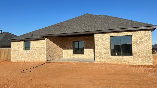 back of property featuring brick siding and a shingled roof