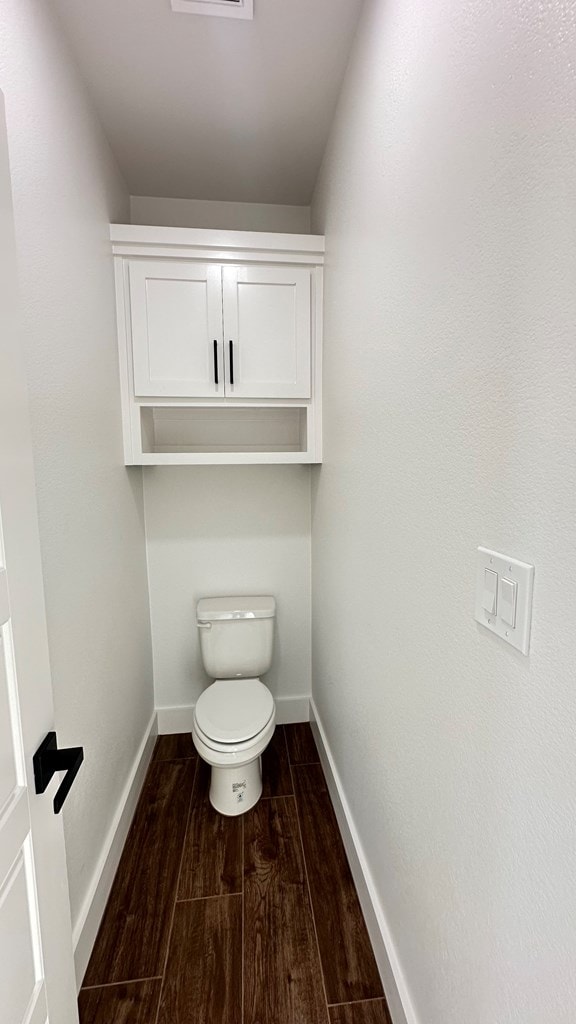 bathroom featuring toilet, wood finished floors, and baseboards