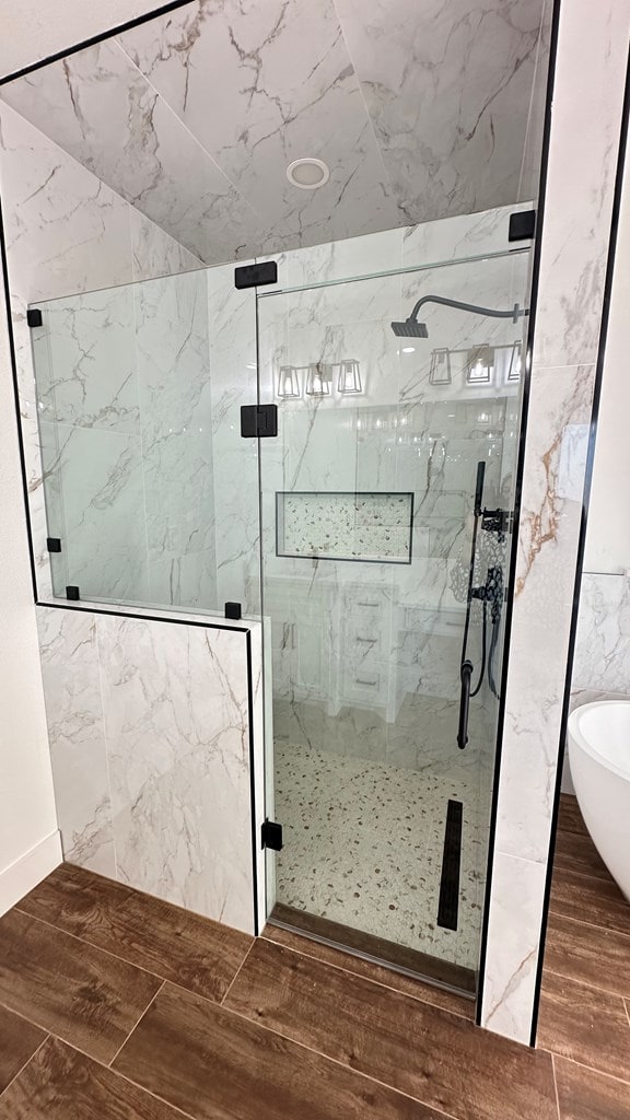 full bath with a marble finish shower, a freestanding bath, and wood tiled floor