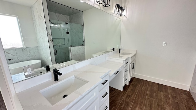 bathroom with double vanity, a freestanding tub, a marble finish shower, and a sink