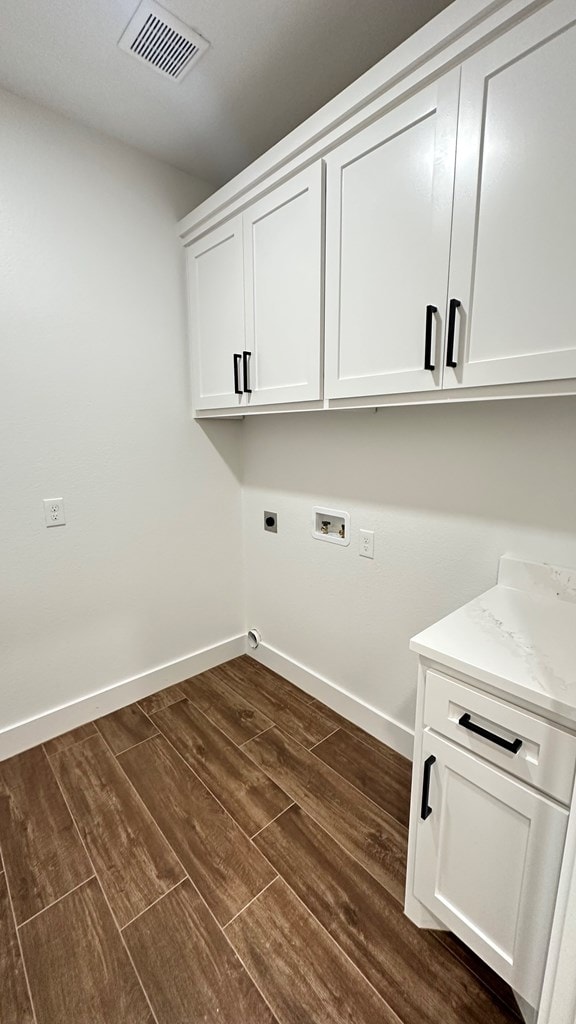 laundry area with visible vents, washer hookup, cabinet space, baseboards, and dark wood-style flooring