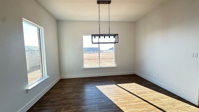 unfurnished dining area featuring dark wood-type flooring and baseboards