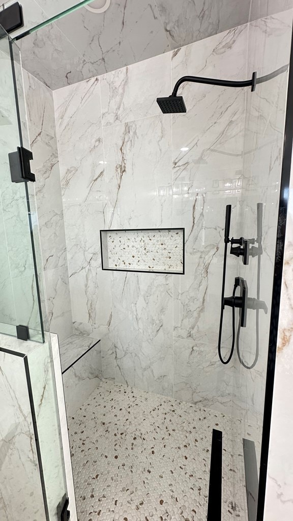 bathroom featuring a marble finish shower