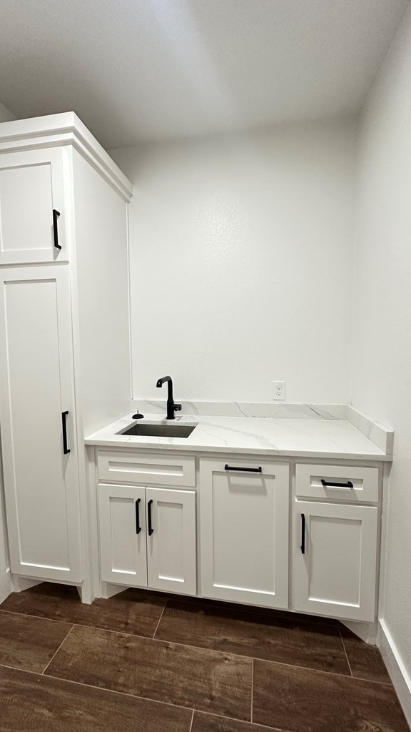 bar with wood finish floors and a sink