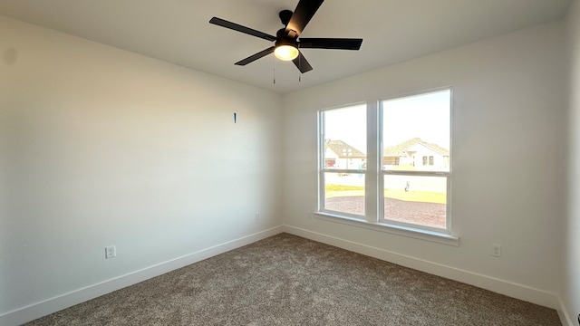 carpeted spare room with a ceiling fan and baseboards