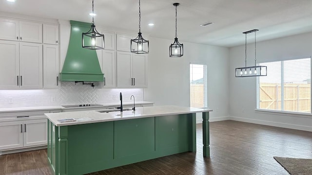 kitchen featuring custom range hood, visible vents, white cabinets, and a sink