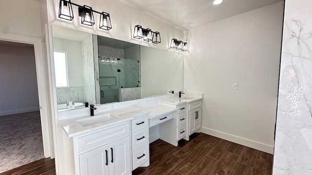 bathroom with a marble finish shower, baseboards, wood finished floors, and vanity