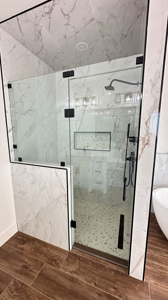 bathroom featuring a soaking tub, a marble finish shower, and wood tiled floor