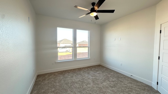 carpeted empty room with a ceiling fan and baseboards