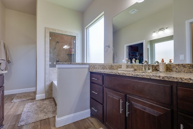 full bathroom featuring walk in shower, vanity, wood finished floors, baseboards, and a walk in closet