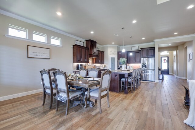 dining room featuring light wood-style flooring, crown molding, baseboards, and recessed lighting